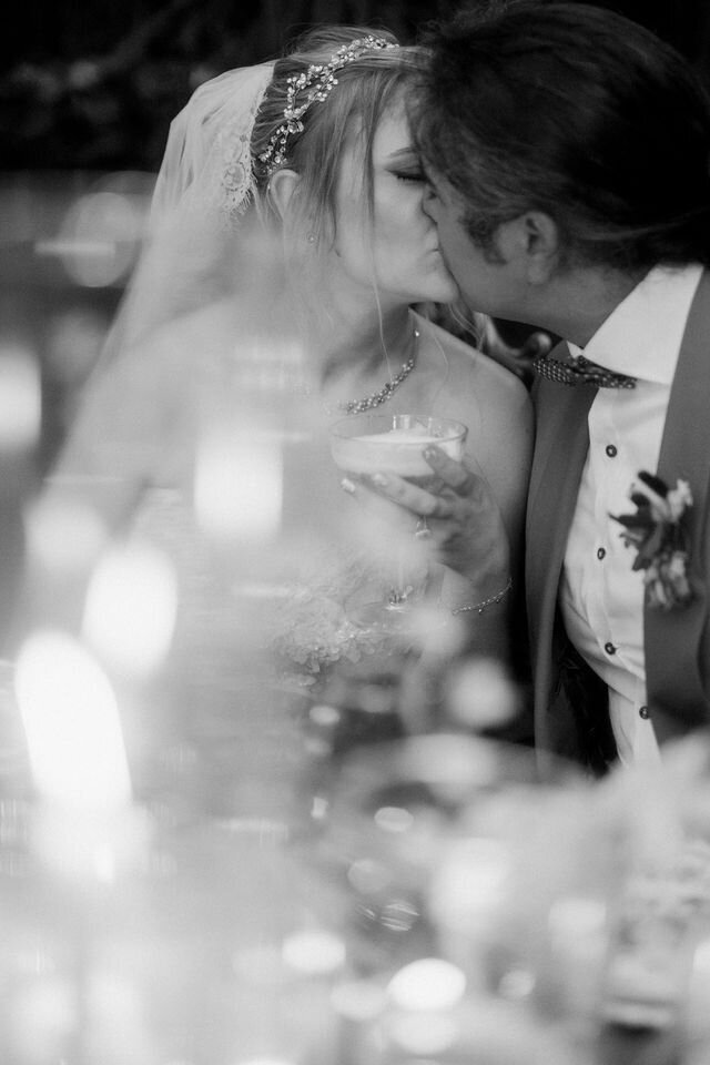 black and white photo of the bride and groom  at reception dinner kissing