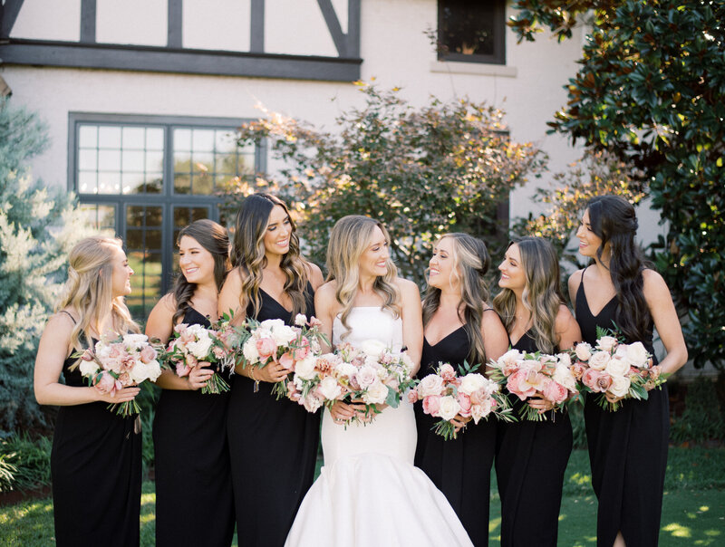 A bride surrounded by her bridesmaids holding bouquets