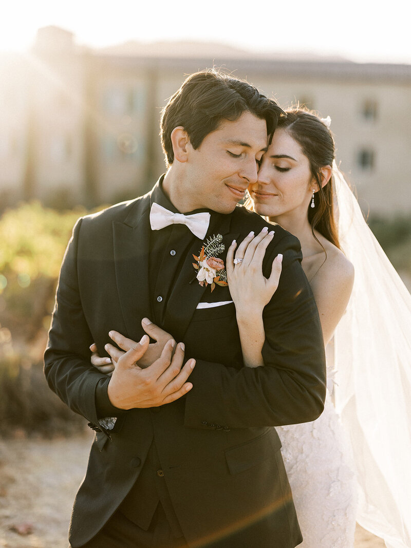  a bride and groom, embrace in the sunset during their California wedding at an Italian inspired resort