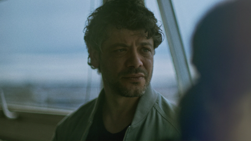 A close-up of a music producer working under atmospheric lighting in a sound studio.