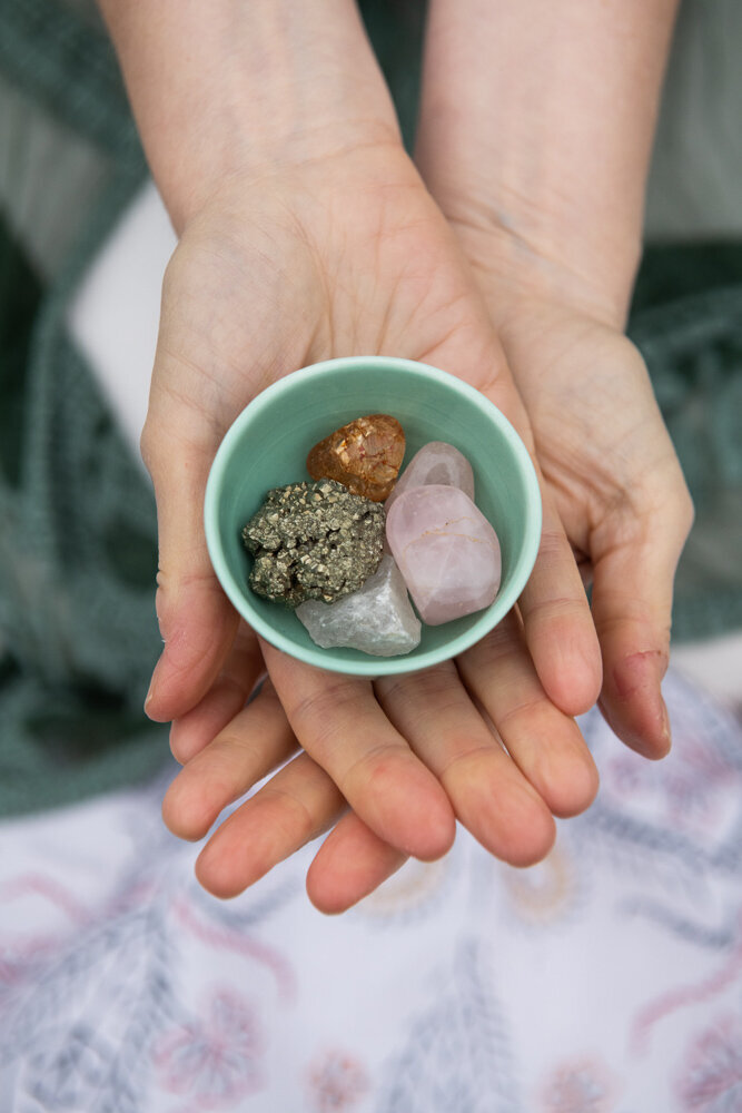 hands holding a blue bowl with crystals