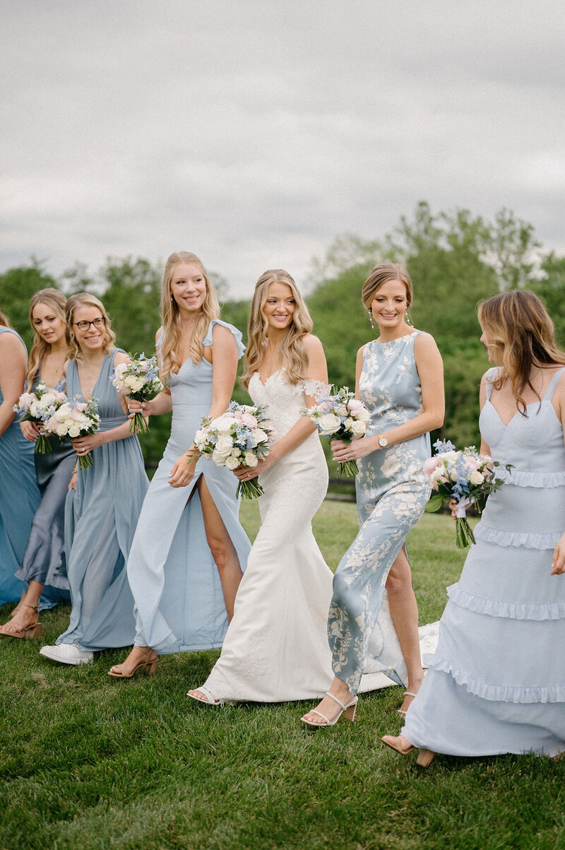 Bride with her wedding party in blue happily walking outdoors