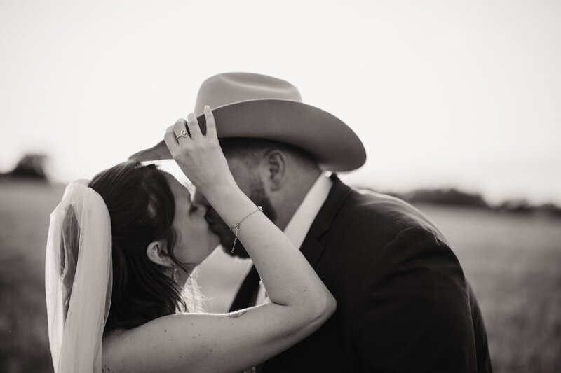 a bride tip hers husbands cowboy hat to sneak a kiss during golden hour photos with Shelly Voss Photography