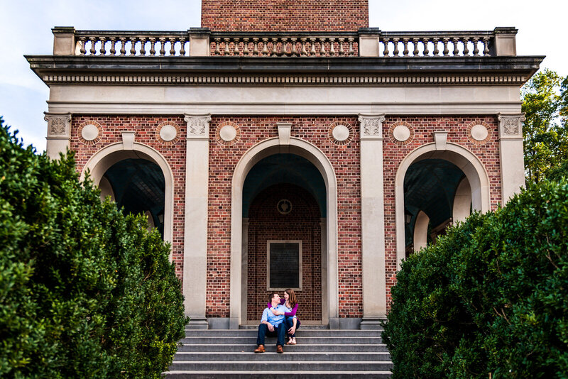 Engaged couple sits on the steps of UNC's bell tower