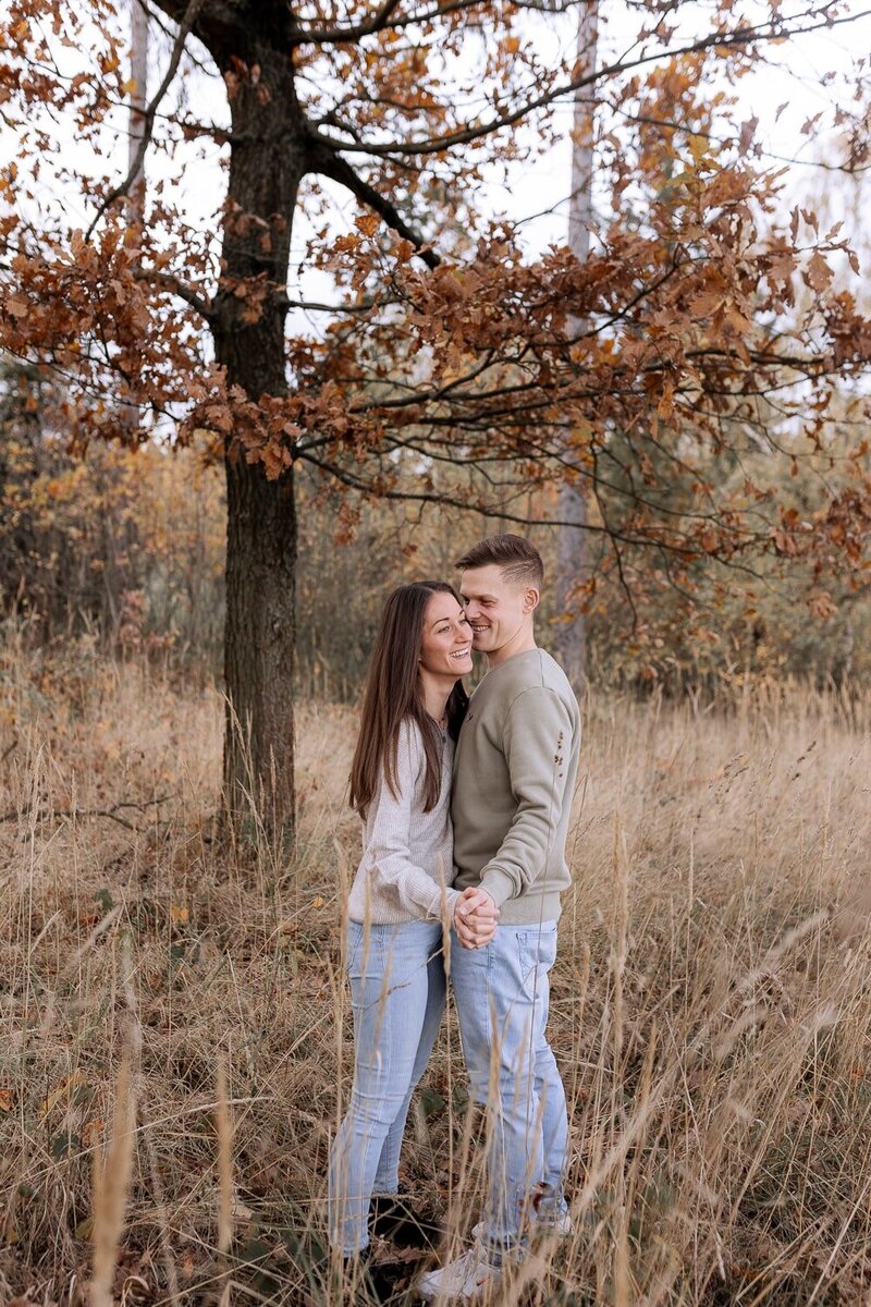 Paar steht im Herbst im Wald und lacht verliebt