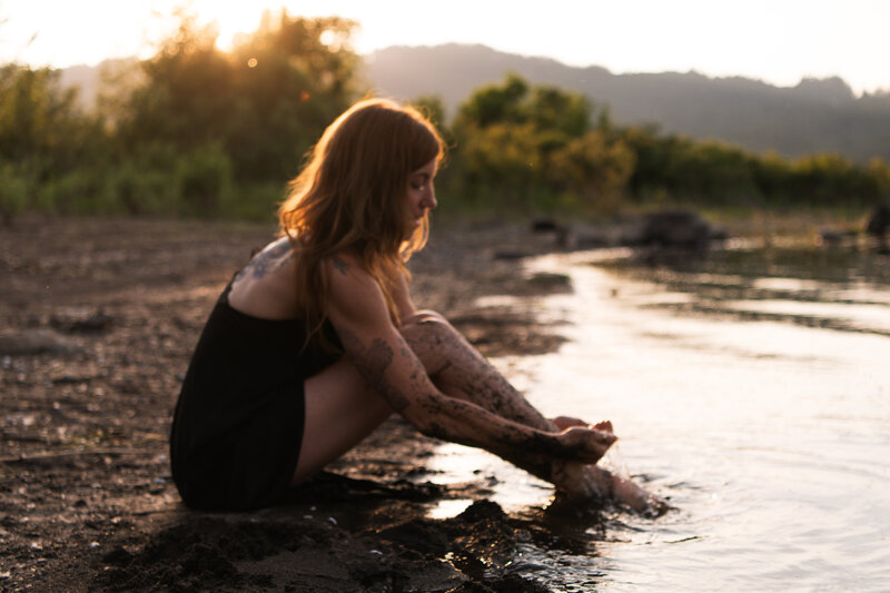 yoga instructor sitting with her feet in the river