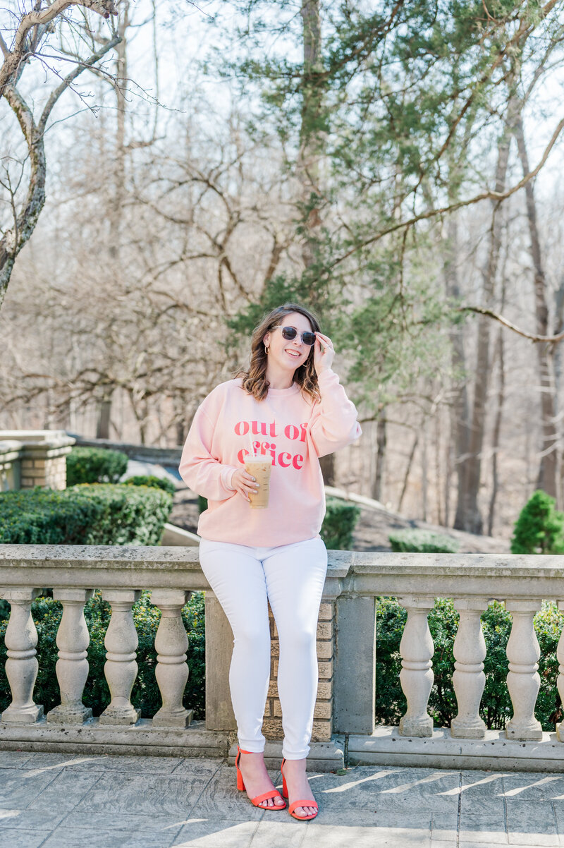 Cait Potter outdoors in a pink sweater holding a coffee