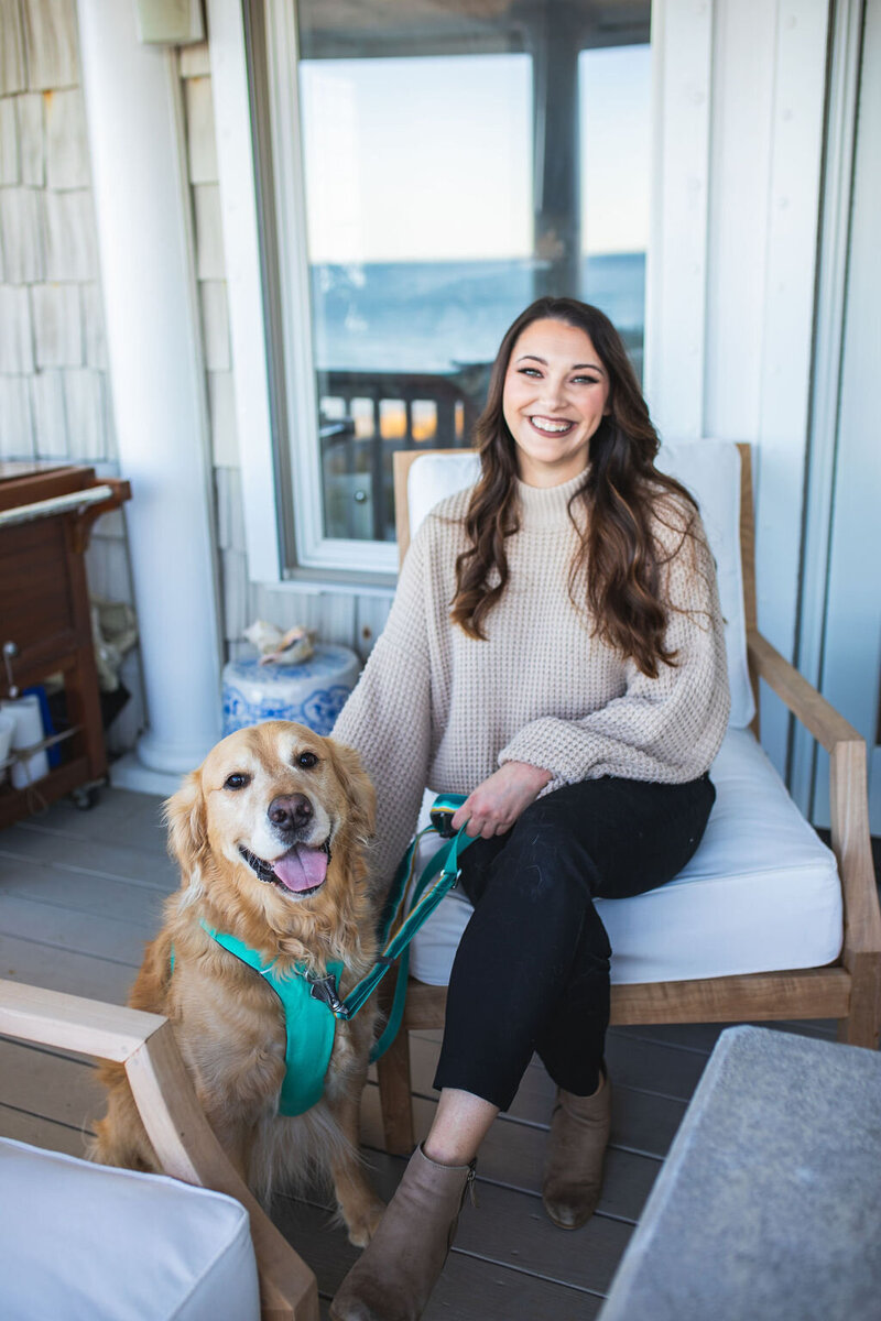 Therapist sitting on chair smiling next to Golden Retriever