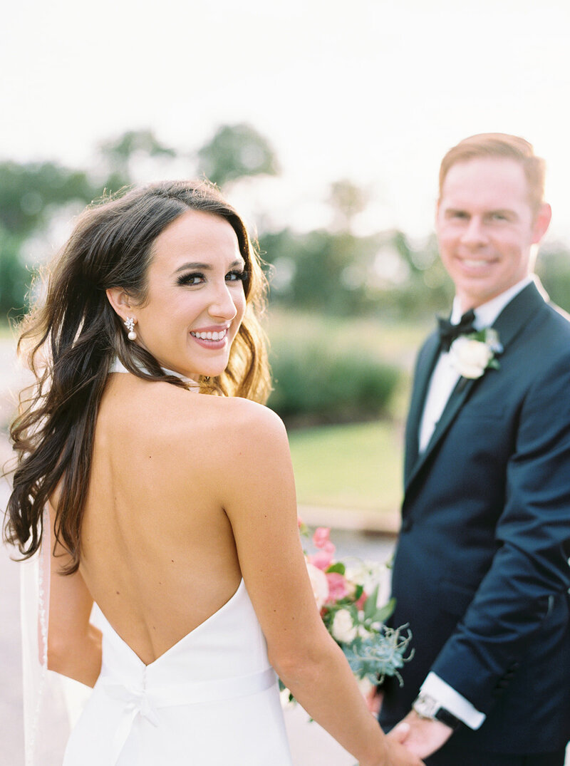 Smiling bride looking over her shoulder at her groom during golden hour portraits, captured at a joyful Austin wedding.