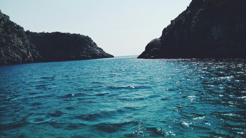 Image of blue water with dark rocks near the beach
