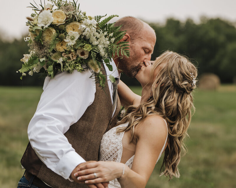 bride and groom kissing with brides veil flowing in the wind
