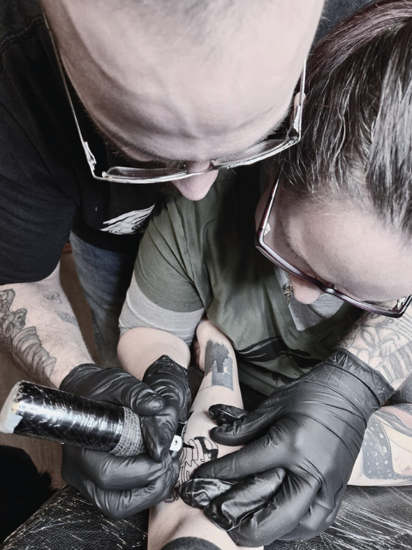 The owner of The Dark Art Collective tattoo studio giving guidance to apprentice at top rated tattoo shop in Tacoma, Washington