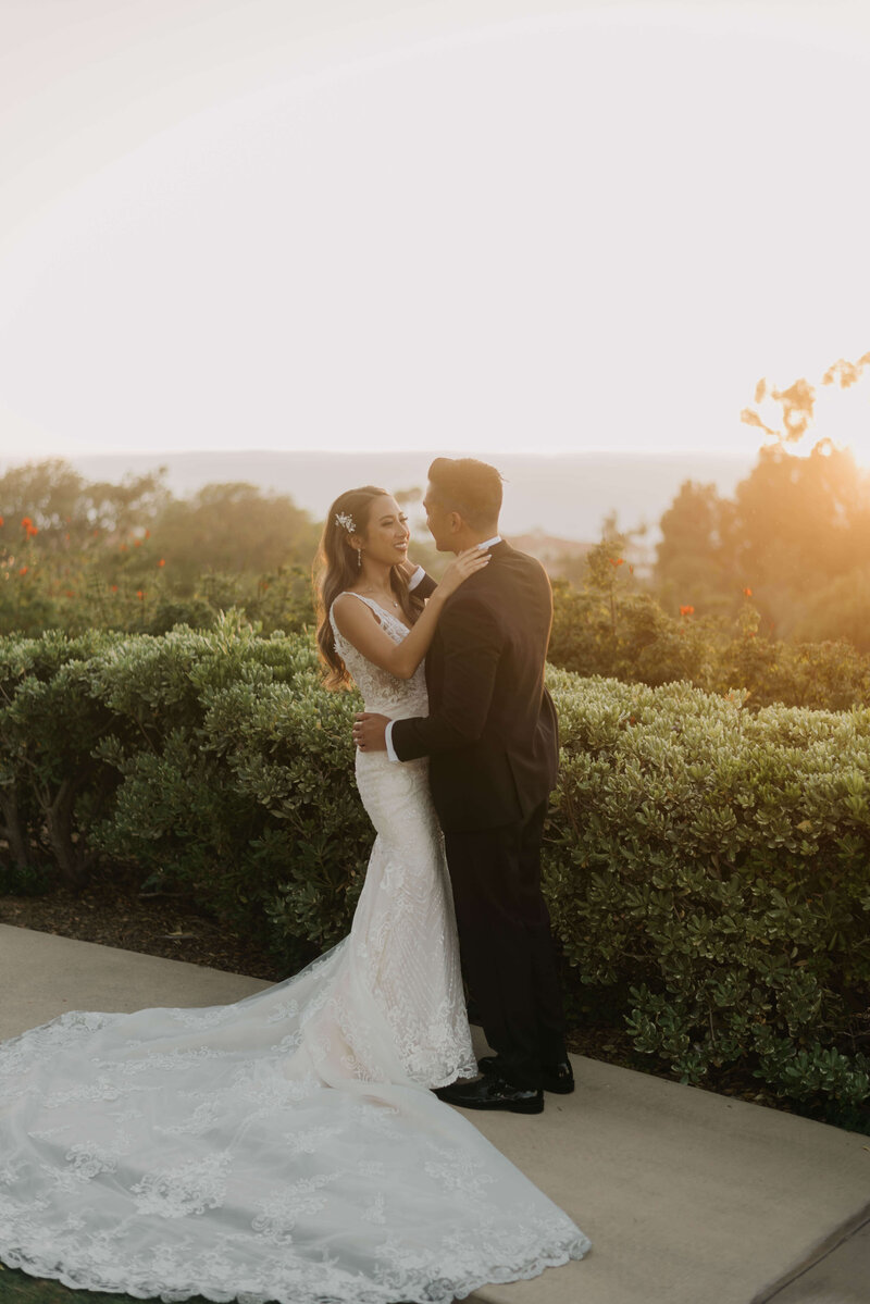 A wedding couple during golden hour share a moment.