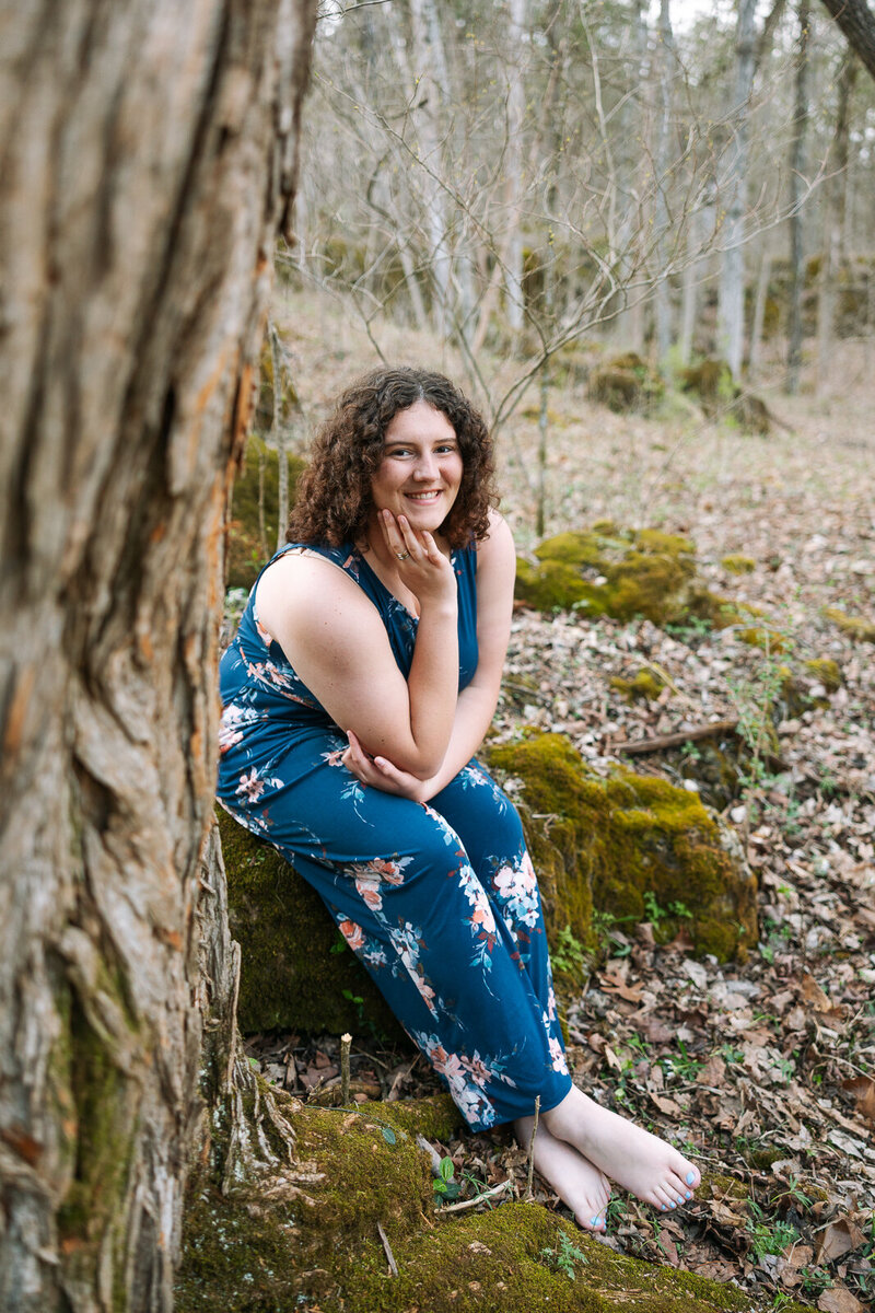 Senior girl sitting in the woods near a tree during a spring session in Bonne Terre, Missouri.  