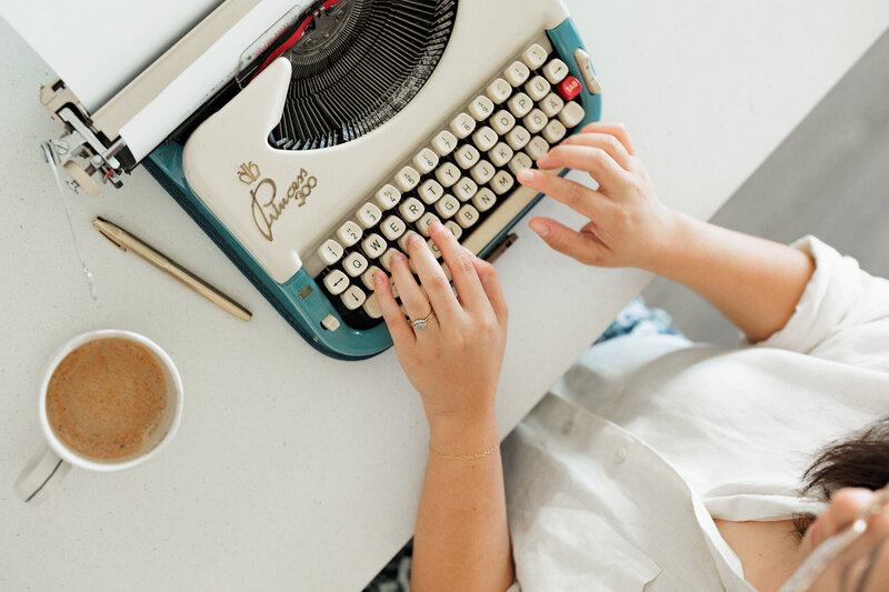 Author typing on typewriter with cup of coffee