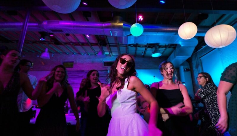 A newlywed dancing with guests at their reception 