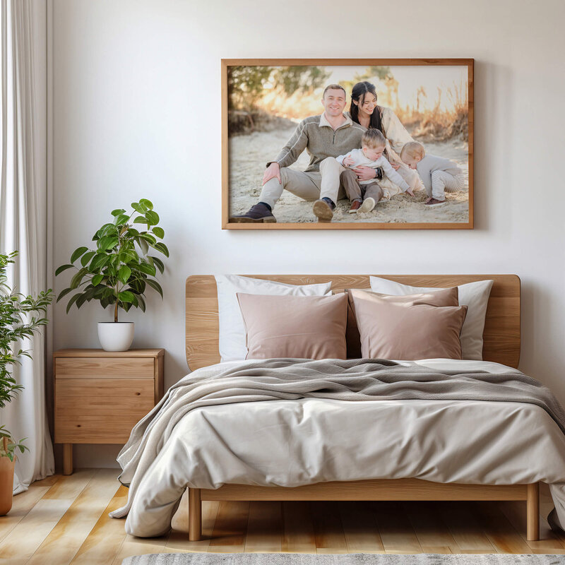 A photo of a family at in the sand at Pleasure House Point hangs above the bed in their room. The family is dressed in neutrals to match their neutral decor.