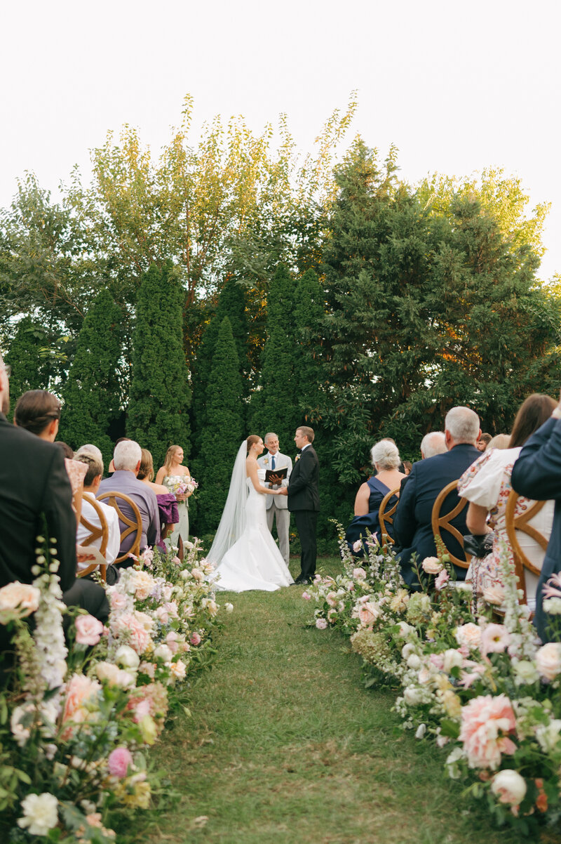 Bride holding pastel bouquet with lace dress details.