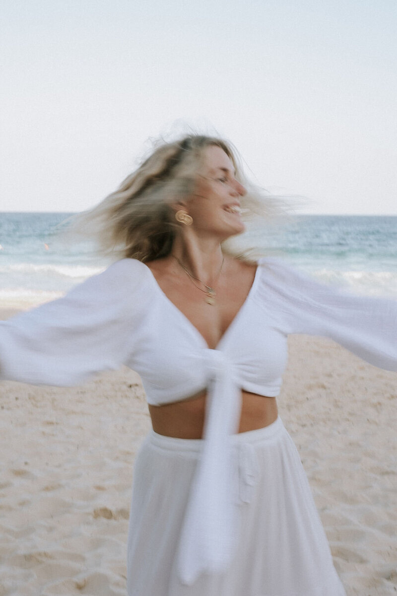 photo of a woman spinning around on the beach