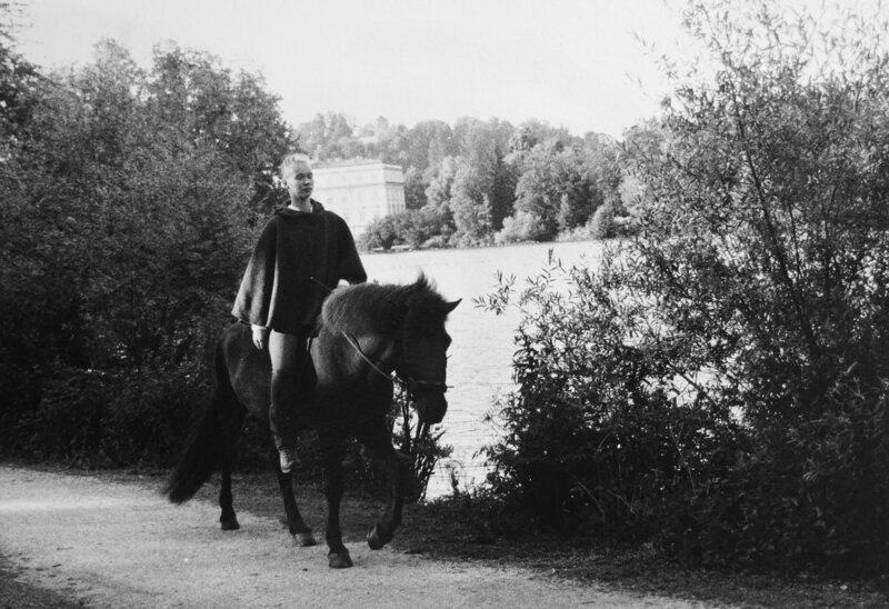 Pferdetrainerin und Pferdemassagetherapeutin reitet ihr Islandpferd in einem dunklen mittelalterlichen Umhang
