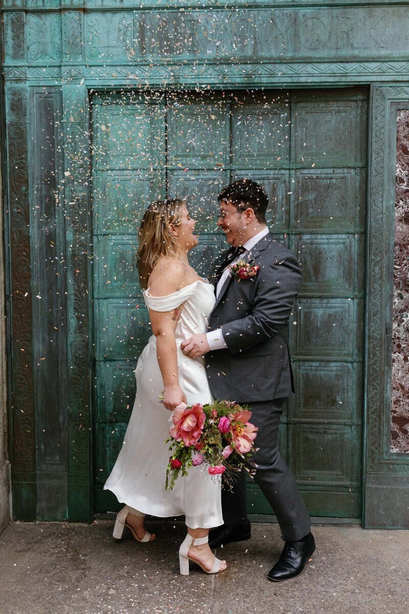 NYC city hall elopement queer couple dancing with confetti and off the shoulder dress