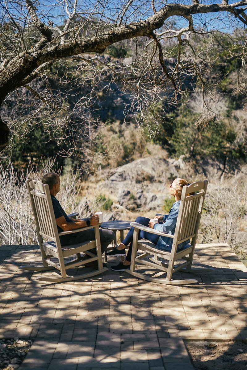 Man and woman sitting in wooden rocking chairs outside