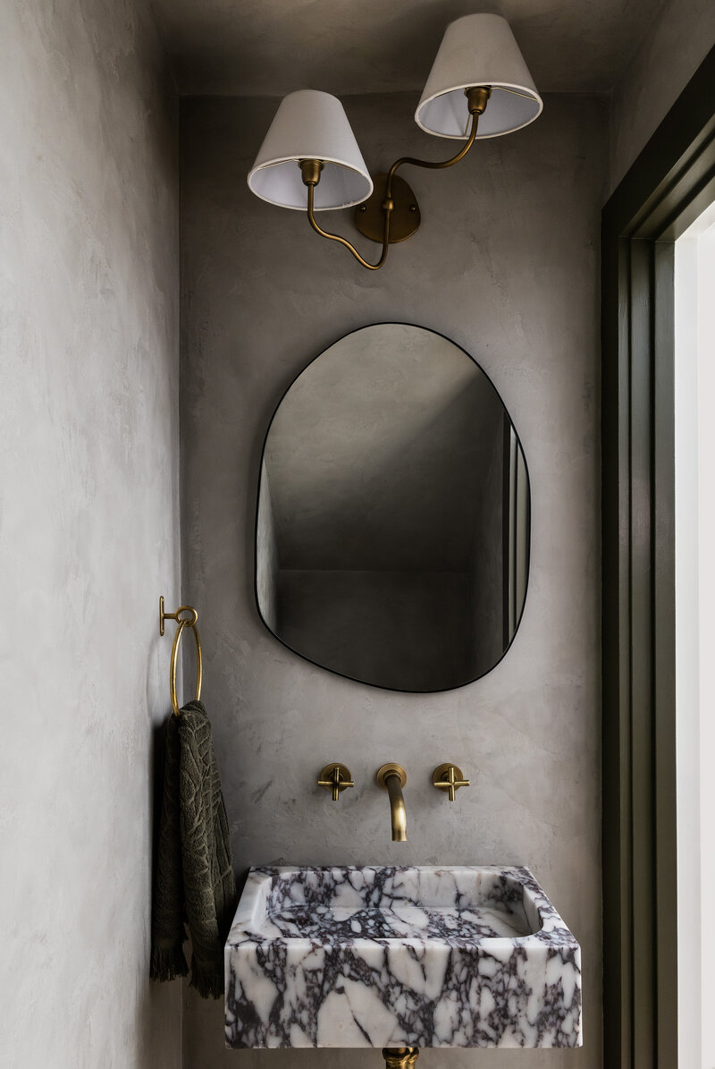 Bathroom with interesting stone sink and wavy mirror.