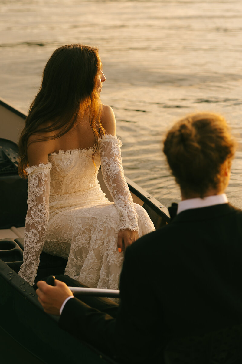 Bride and groom sitting in canoe looking towards the susnet