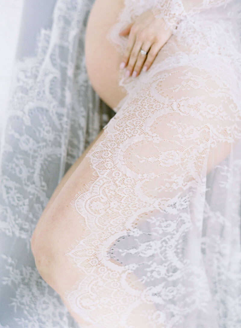 White lace envelopes pregnant belly during boudoir maternity session with Jacqueline Benet