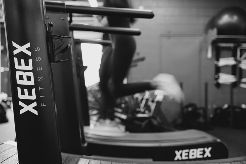 brand photographer captures candid photo of personal trainer running on a treadmill edited in black and white