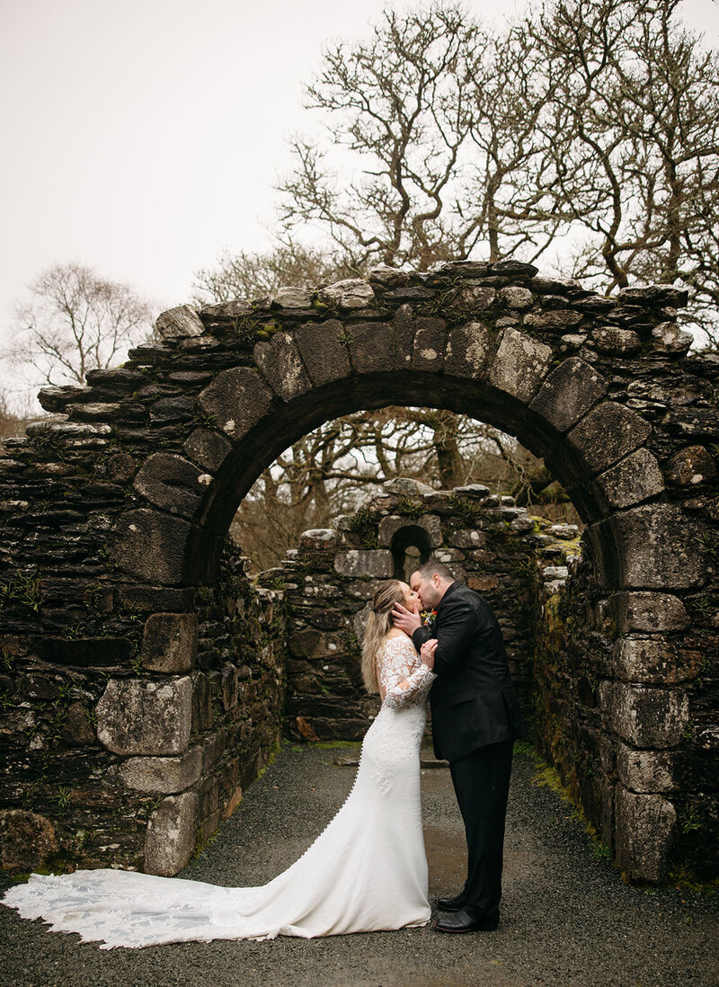 A couple shares a romantic moment under an ancient stone archway