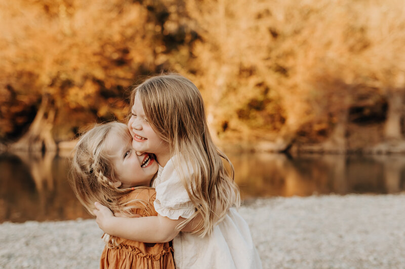 Two toddler girls hugging and giggling while having their photos made for a San Antonio photography sesssion.