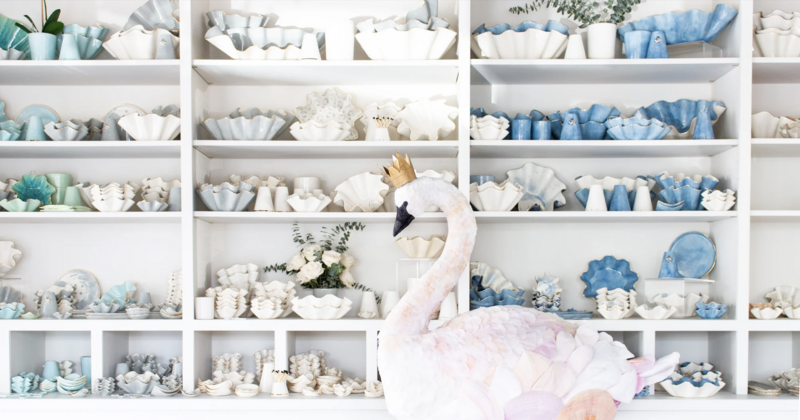 Swan decor sitting in front of tall shelves of scallop edge pottery bowls