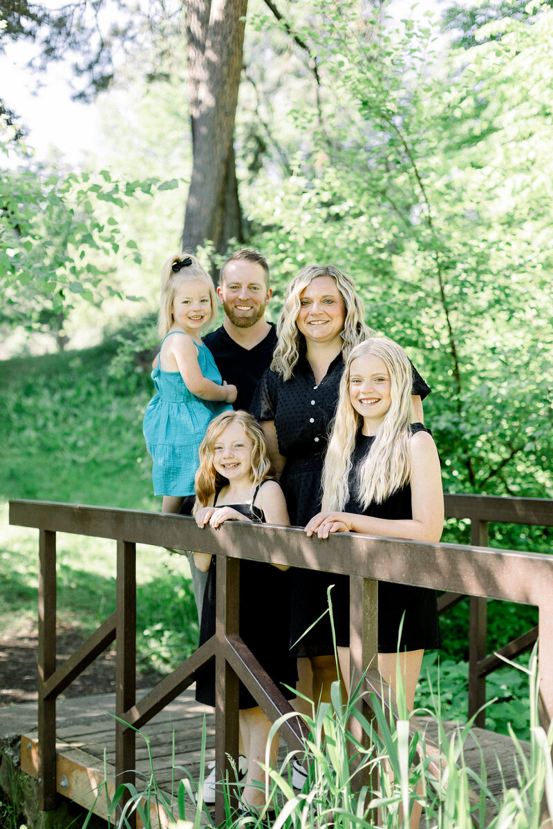 family cuddled together on a bridge smiling taken by spokane family photographer