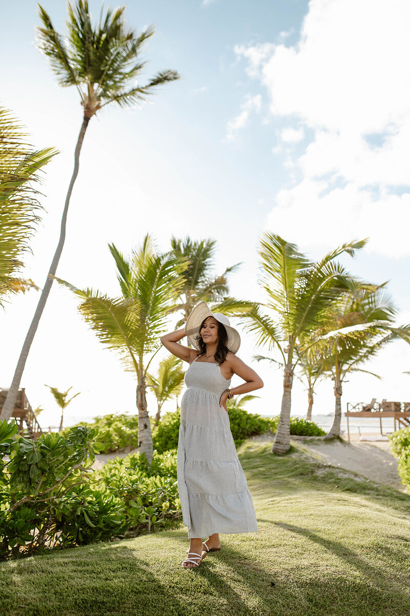 Photo of Carol with beach hat and beach dress on hill with palm trees