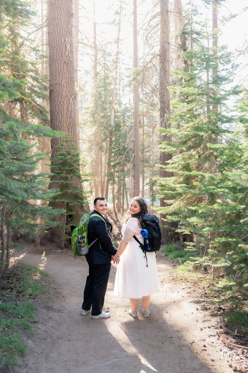 Yosemite National Park elopement at Taft Point with bride and groom hiking in forest at sunset.