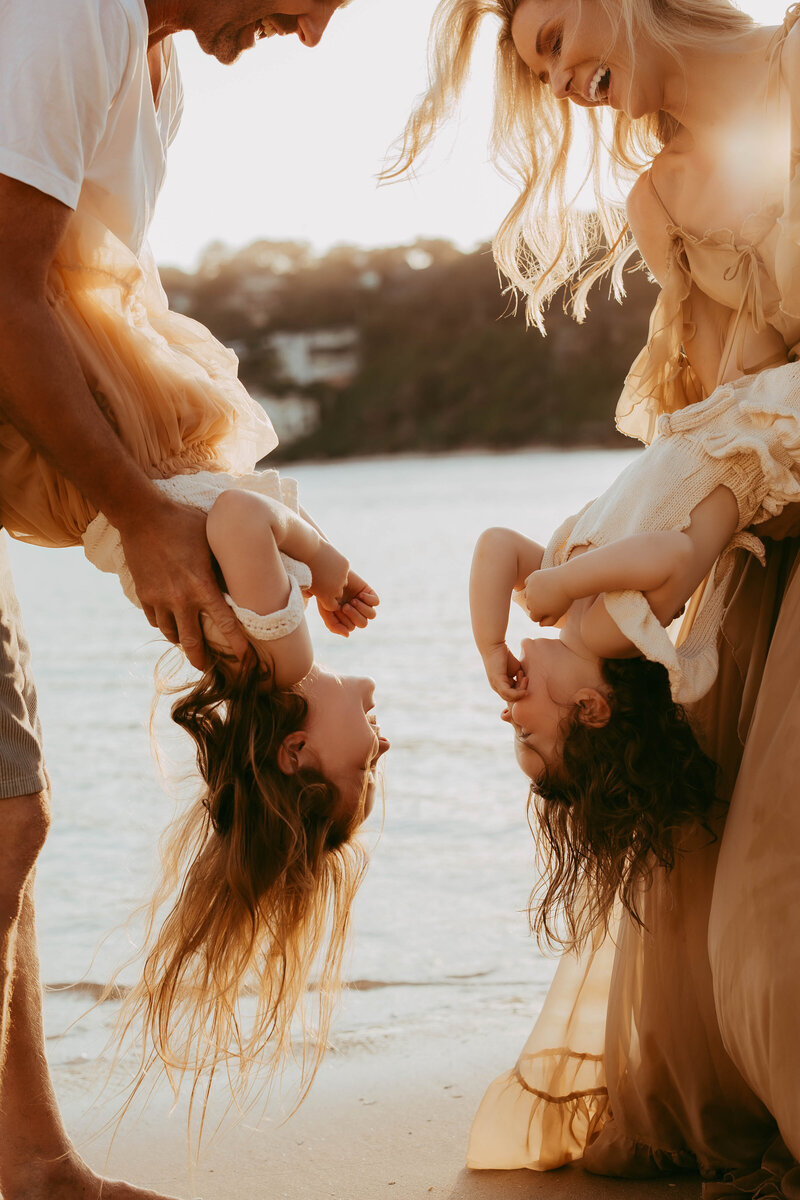 Parents holding child by the hands while walking at the beach, photographed by Sydney family photographer Sophie Lea.