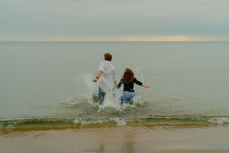 Beach photoshoot of couple running in ocean