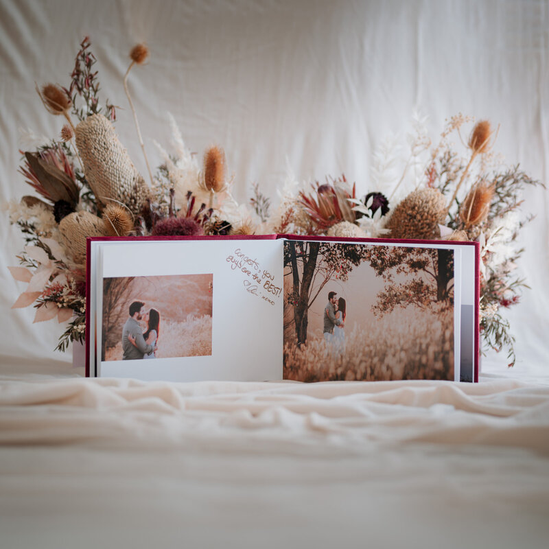 Open pages of a guest book front of a dried flower arrangement