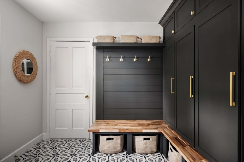 Functional mudroom design with custom storage cabinets, wood bench, and decorative tile floor.