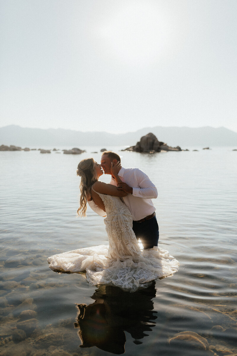couple kissing in their wedding attire knees deep in lake tahoe