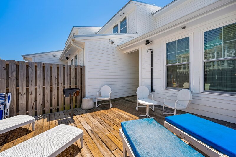 Sun-drenched private patio with loungers, grill, and outdoor shower at Beach Cabana vacation townhouse near Panama City Beach, Destin, and Santa Rosa Beach.