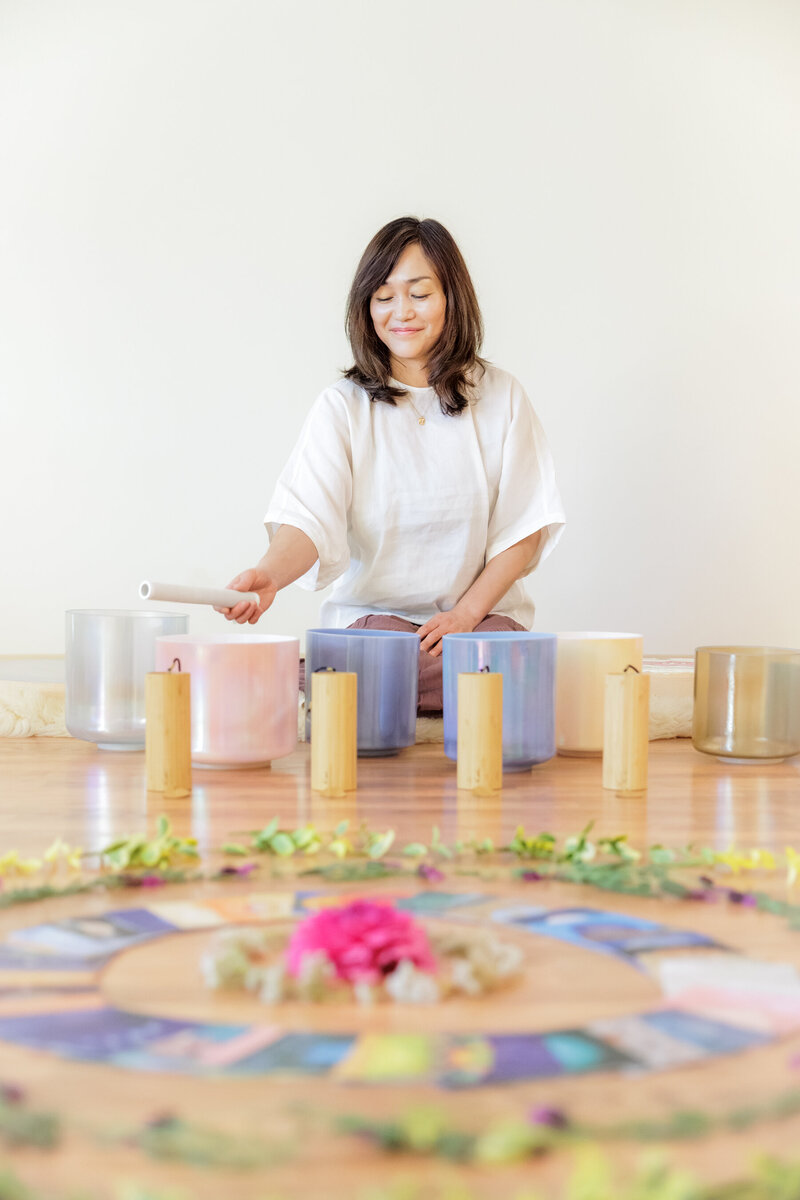 Lifestyle shot of reiki master woman playing sound bowls during a sound bath personal branding session