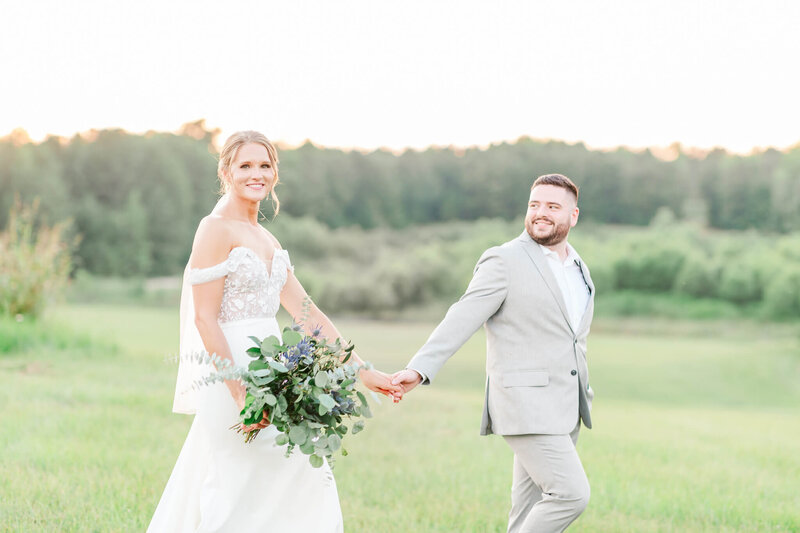 Bride and groom walking in a field at sunset Bride and Groom dip kiss in front of Marriott Grand National | Opelika Wedding Photographer Amanda Horne