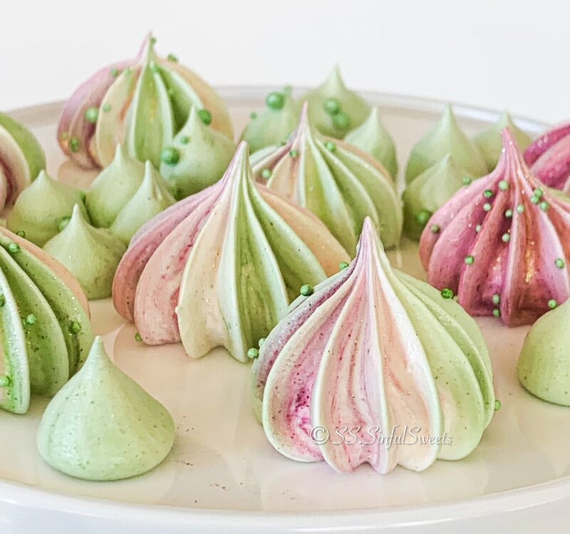 Pink and green meringue cookies decorated with green sprinkles.