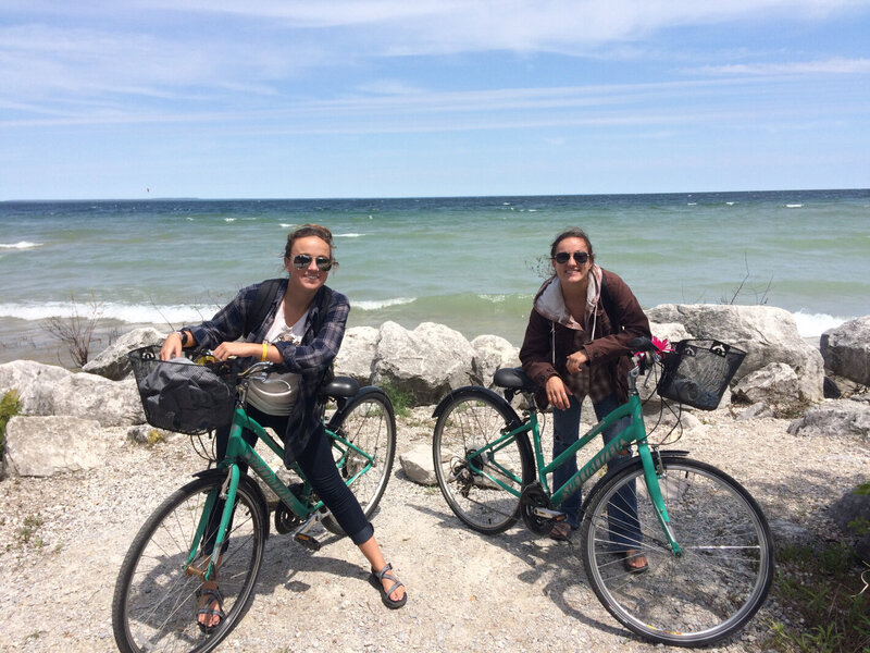 Two girls pose by the oceans edge with their beach cruisers .