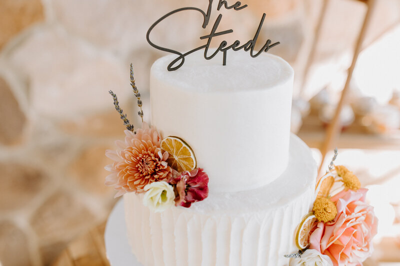 multi-tiered white wedding cake with flowers placed throughout it