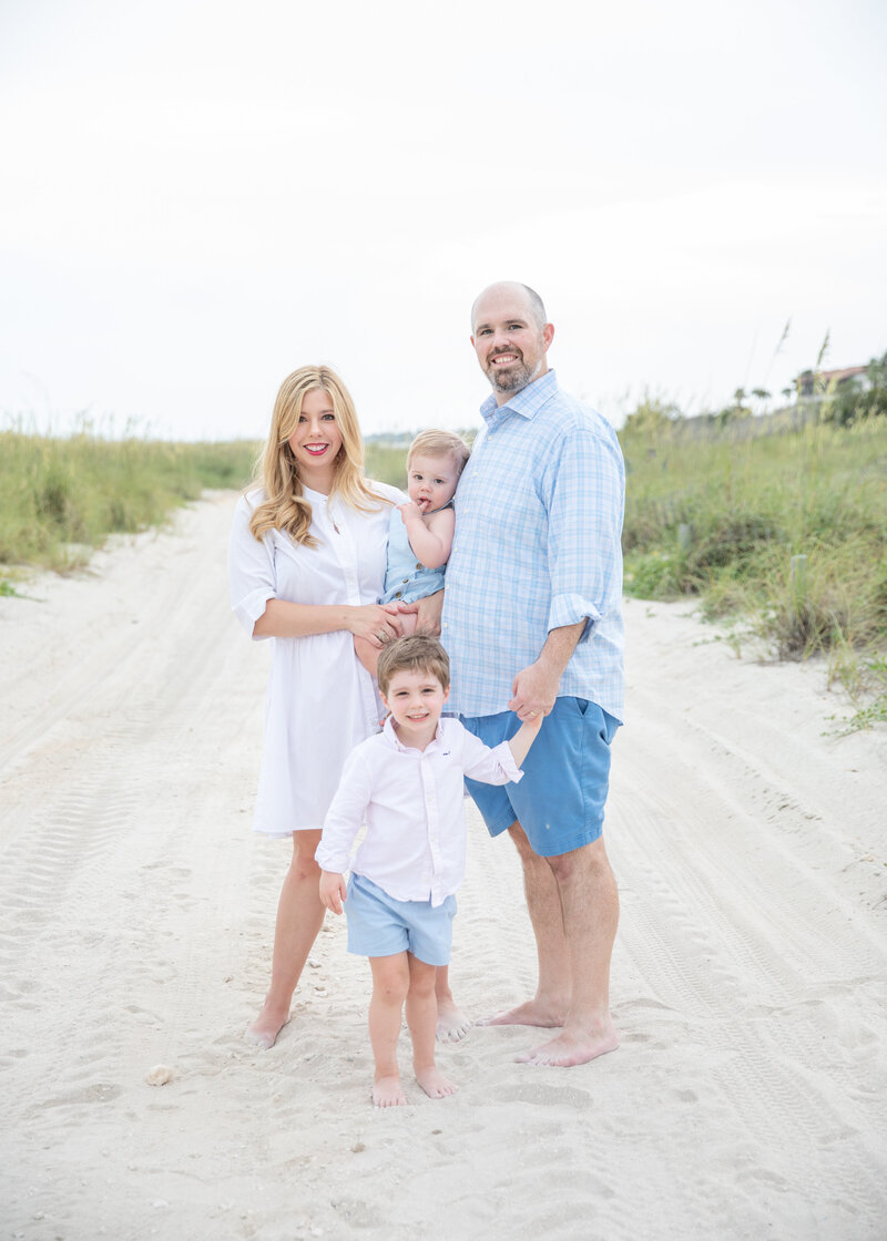 family of four on vacation photographed at the sea island beach club with the sea oats in the background
