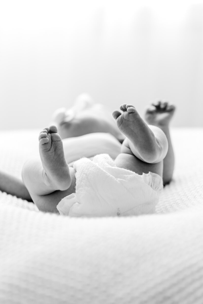 A black and white photo of a newborn baby's feet kicking in the air by DC Maternity Photographer