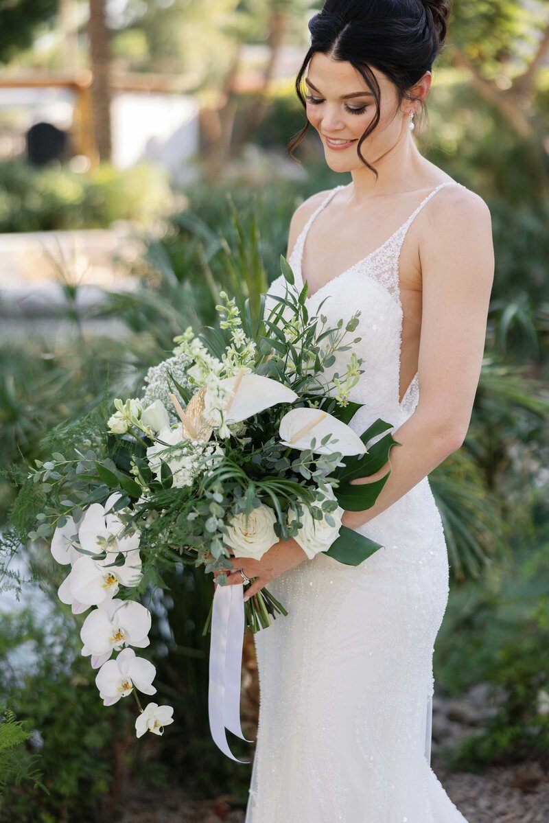  Bride smiles and looks down at her tropical bouquet.